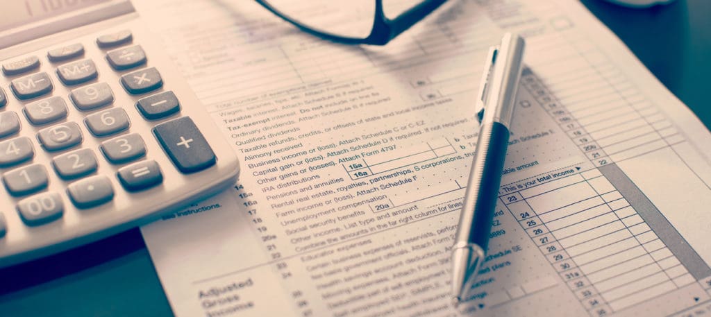 Background Image featuring a calculator, pen, and financial paperwork.