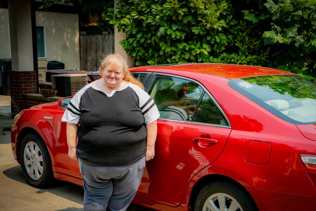 Former Resident Jennifer stands by her car.