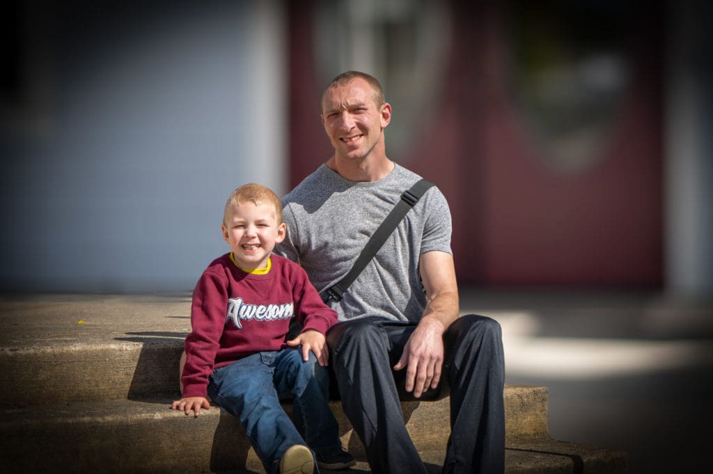 Skyler and his Son sit on the Mission steps.